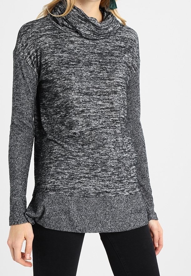Femme portant un pull en maille gris chiné à manches longues avec un col bénitier ample et un pantalon noir.