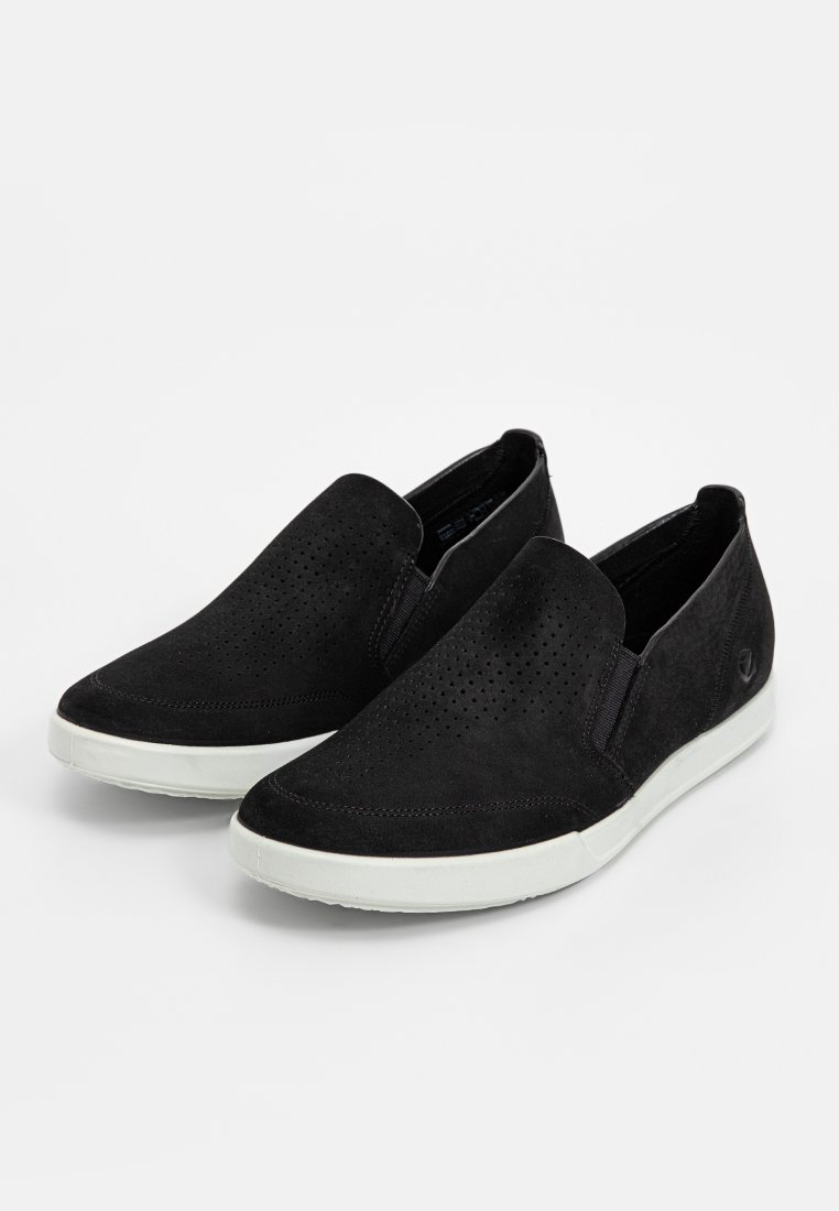 Svarta slip-on skor i mocka, med perforerat överdel för andningsförmåga, vit gummisula och minimalistisk design.