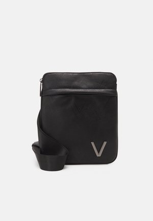 Borsa crossbody nera con un motivo geometrico, texture liscia e un accento metallico a forma di "V". Presenta una chiusura a zip e una tracolla removibile.