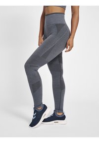 Szare legginsy z wysokim stanem z teksturowanymi wzorami i dopasowanym krojem, w połączeniu z granatowymi butami sportowymi z jasnoniebieskimi detalami.