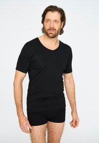 Zwarte korte mouwen V-hals T-shirt van zachte stof, gecombineerd met zwarte boxershorts. De pasvorm is strak en heeft een soepele textuur.