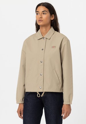 Beige leichte Jacke mit einem Kragen, Druckknöpfen und zwei Seitentaschen. Enthält elastische Bündchen und einen Kordelzugsaum.