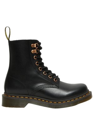 Bottine en cuir noir à lacets, avec des coutures jaunes, des œillets en métal et une languette à l'arrière.