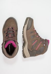 Scarponi da trekking marroni e grigi con dettagli rosa e suole robuste, una scarpa mostrata vista dall'alto, l'altra di lato su sfondo bianco.