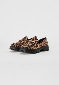 Leopardų rašto loaferiai su tekstūruota paviršiumi, auksinėmis detalėmis ir masyviu juodu guminio pado konstrukcija, užtikrinančia geresnį sukibimą.