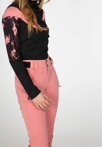 Haut à manches longues noir et rose avec une manche noire texturée. Pantalon ajusté rose avec poches zippées et détail ceinture. Finition en tissu lisse.