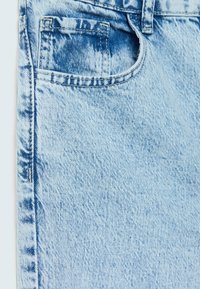 Tela de mezclilla azul claro con un diseño clásico, con costuras visibles, textura y un pequeño detalle en el bolsillo trasero.