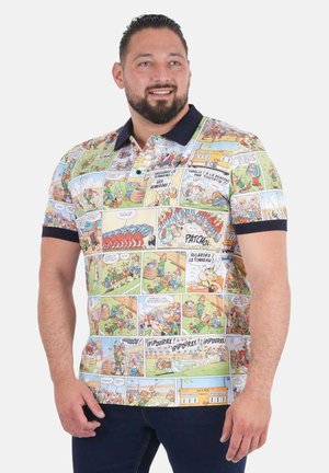 Homme portant un polo à manches courtes imprimé de vignettes colorées de bandes dessinées, debout devant un fond uni.