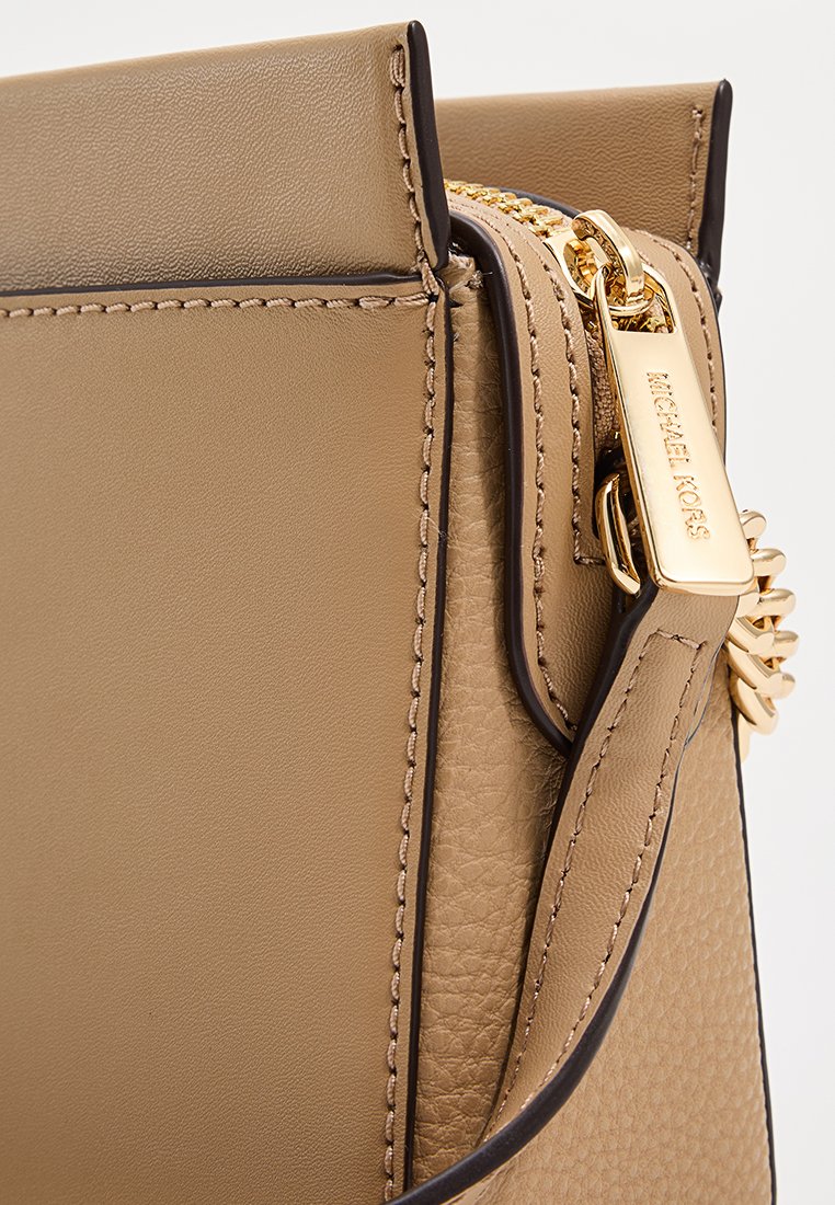 Tan leren handtas met een gestructureerde afwerking, gouden rits en hardware, en een band met een logo-accent. Strakke lijnen en een minimalistisch ontwerp.