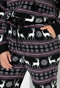 Conjunto de forro polar negro con un patrón de renos y copos de nieve, con acentos en rosa y blanco. Incluye una cinturilla con cordón y bolsillos laterales.