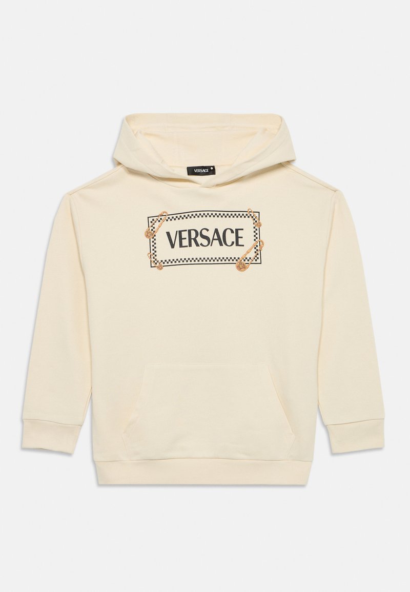 Sweatshirt com capuz creme, apresentando um bolso frontal e um gráfico com marca e borda preta, adornado com detalhes de alfinetes de segurança.