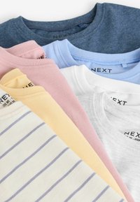Assortiment van crew-neck t-shirts in verschillende kleuren: donkerblauw, roze, lichtblauw, wit, geel (met strepen) en grijs. Labels zichtbaar.