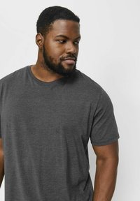 Camiseta de cuello redondo en color gris, hecha de tela suave. Mangas cortas, corte regular y diseño minimalista sin patrones ni marcas visibles.