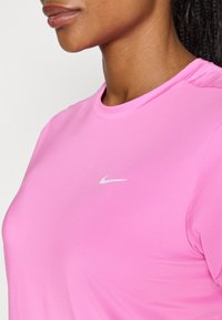 Ružová športová tričko s krátkym rukávom značky Nike. Hladký povrch, okrúhly výstrih, s jemným bielym logom na hrudi.