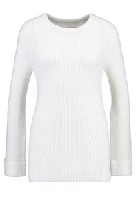 Valkoinen neulepusero, jossa on ribbikuvio, pyöreä pääntie ja pitkät hihat. Hihansuut ovat myös ribbien, mikä luo tiukemman istuvuuden.