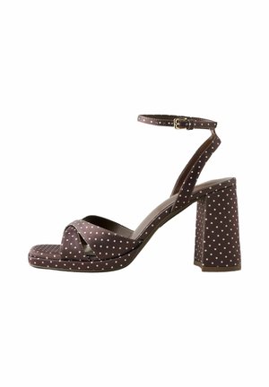 Braune High-Heel-Sandale mit weißen Punkten, Knöchelriemen mit Schnalle, überkreuzten vorderen Riemen und breitem Absatz.