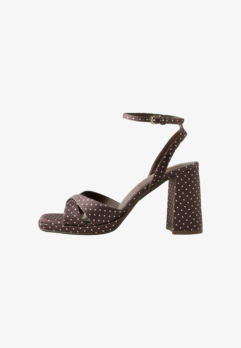 Sandale à talons hauts marron à pois blancs, bride de cheville avec boucle, lanières croisées à l'avant, et talon bloc.