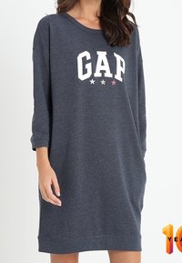 Tummanharmaa collegehamonen rentoa istuvuutta, pyöreä pääntie, kolmanneslangan hihat ja valkoinen "GAP" -grafiikka värikkäillä tähdillä.
