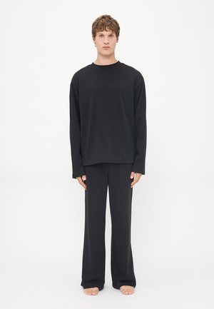 Schwarzes Loungewear-Set mit einem Langarm-Shirt mit Rundhalsausschnitt und lockeren Hosen, hergestellt aus einem weichen Stoff mit glatter Textur.