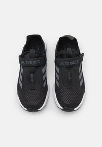 Schwarze Sportschuhe mit einem Mesh-Obermaterial, ausgestattet mit grauen Akzenten und einem Klettverschluss. Gummisohlen und ein runder Zehenbereich für Komfort.