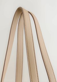 Beige Leder-Schulterriemen mit einer strukturierten Oberfläche, die kontrastierende Nähte und glatte Kanten aufweisen. Drei übereinanderliegende Riemen sind abgebildet.