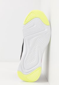 Černá sportovní podrážka s bílým základem a texturovanými vzory; žluté akcenty na špičce a patě pro lepší přilnavost.