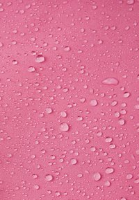 Ροζ ύφασμα με υφή στην επιφάνεια, εμφανίζοντας σταγόνες νερού διαφόρων μεγεθών που δημιουργούν ένα διακοσμητικό μοτίβο.