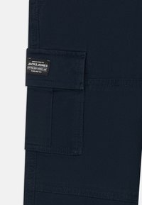 Pantaloni cargo blu con dettagli cuciti a vista e etichetta a toppa. Presentano una tasca laterale e un tessuto resistente.