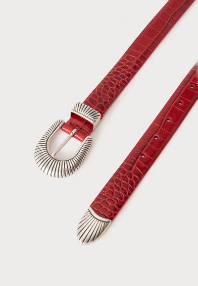 Ceinture en cuir rouge texturé avec boucle décorative argentée, passant et embout, présentée à plat sur fond blanc.