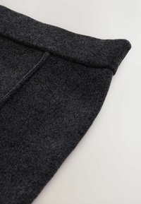 Tumši pelēks tekstila apģērbs ar mīkstu, struktūrētu virsmu, salocītu jostasvietu, noapaļotu apakšu un tīru šuvju detaļu.