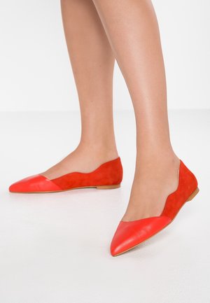 Ballerines rouges avec un bout pointu, combinant cuir lisse et daim, avec un petit talon et un design découpé en vagues sur les côtés.
