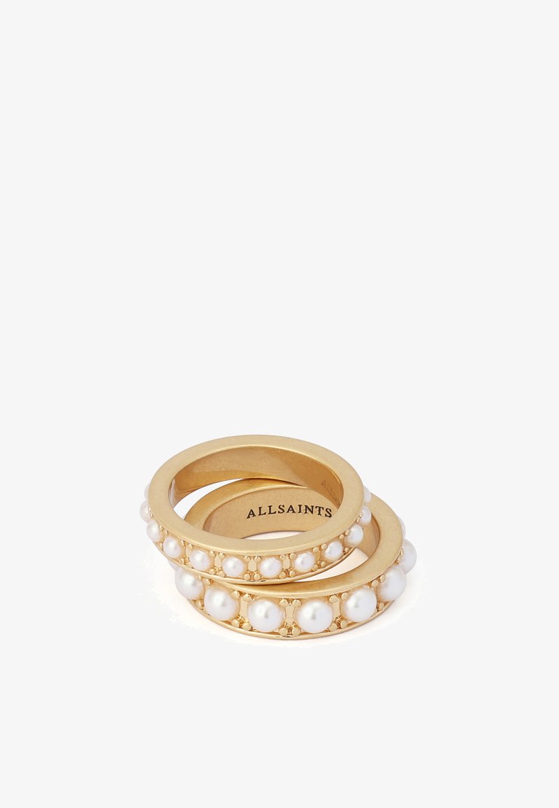 Deux bagues en or avec des perles blanches incrustées, empilées, affichant le nom de la marque "ALLSAINTS" à l'intérieur d'une bague.