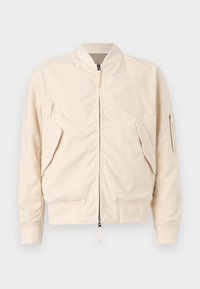 Veste bomber beige en tissu résistant avec fermeture éclair à l'avant. Comprend deux poches latérales, une poche zippée sur la manche, et des poignets côtelés.