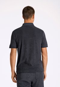 Tummanharmaa lyhythihainen poolopaita, jossa on teksturoitu kangas ja klassinen kaulus. Näytetään takaa, jolloin näkyy hienovaraista ompelua.