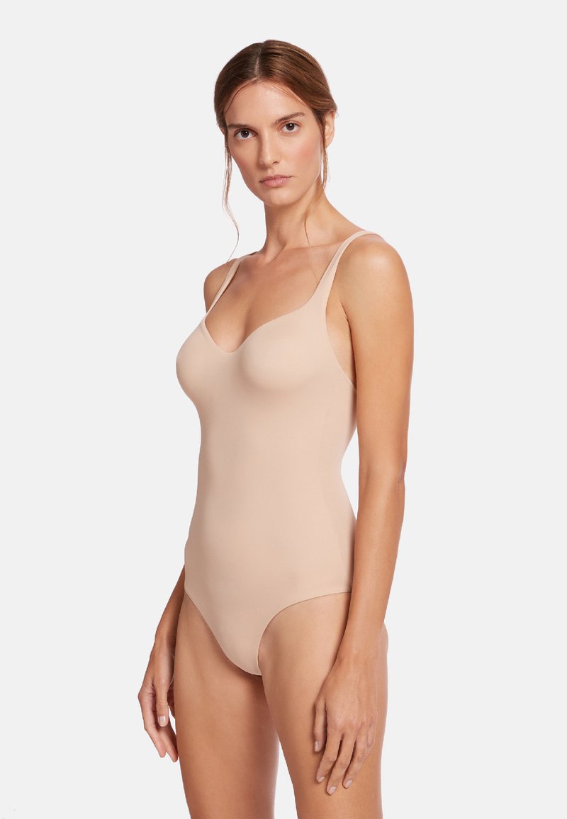 Nude bodysuit med tunna remmar, slät textur och en åtsittande design. Har en rundad halsringning och hel täckning på botten.