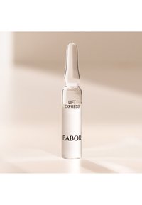 Ampoule en verre clair avec un sommet effilé, contenant un sérum transparent. L'étiquette indique "LIFT EXPRESS" et "BABOR" en caractères noirs.