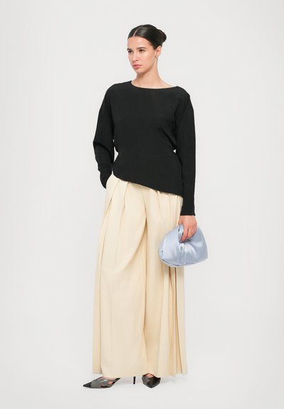 Black long-sleeve top, cream pleated wide-leg pants, gray pointy-toed heels, and a light blue satin clutch. Minimalistic design, soft textures.