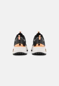 Černé sportovní boty se bílou mezipodešví, měděnými akcenty a texturovanou gumovou podrážkou, s poutky na patě pro snadné obouvání.