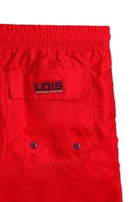 Shorts de cintura elástica roja con un bolsillo trasero que presenta botones de presión azules y una etiqueta negra que dice "LOIS JEANS & JACKETS". Textura suave.