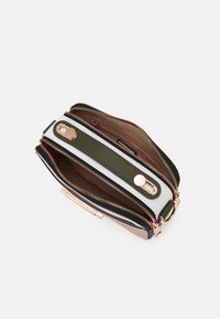 Kieszeń na zamek błyskawiczny z wieloma przegródkami, z czarno-białymi panelami, oliwkowozielonymi akcentami i elementami w kolorze różowego złota. Gładka faktura.