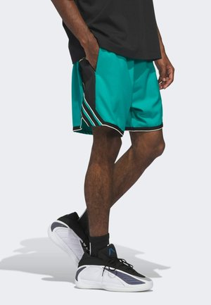 Turkusowe spodenki sportowe z czarno-białymi akcentami, z bocznymi kieszeniami i paskowanymi detalami. Zestawione z czarnymi butami sportowymi.