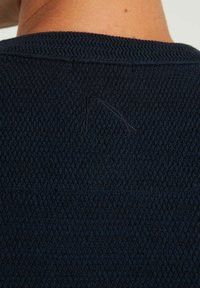 Pull marin tricoté avec un motif texturé, présentant un petit détail de point près de l'encolure. Tissu doux avec une coupe ajustée.