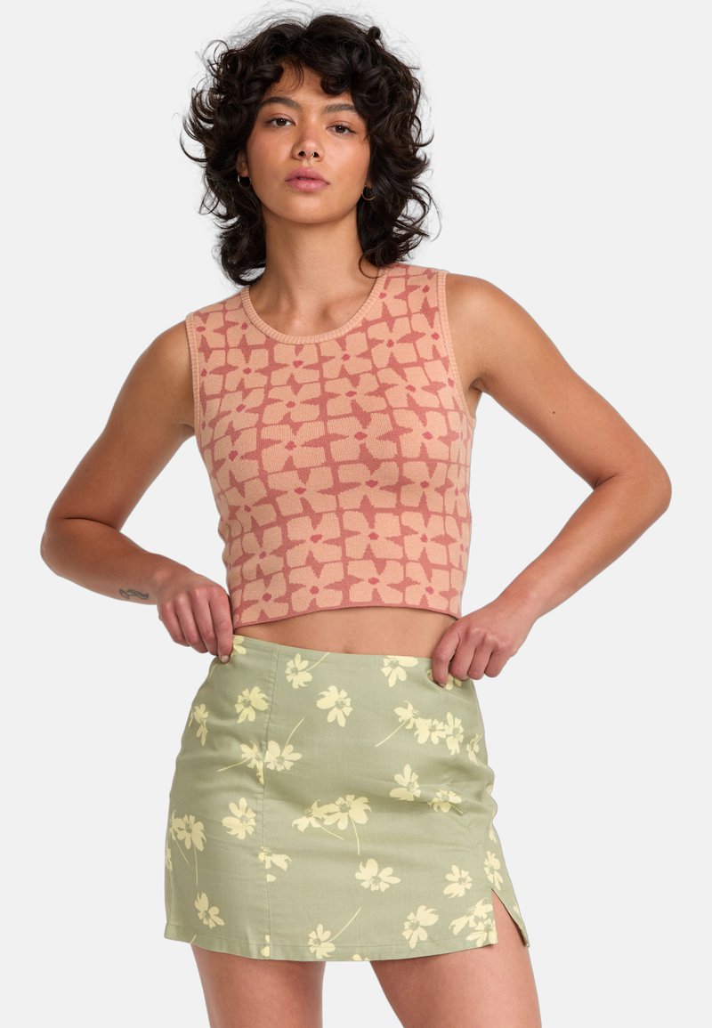 Crop top in light pink with a grid pattern, paired with a short green skirt featuring a floral print and side slit. Both are fitted.