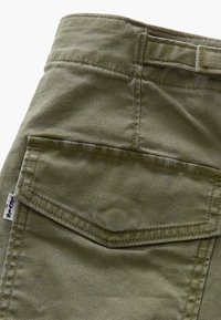 Poche d'un pantalon cargo en tissu vert olive avec rabat et étiquette blanche Levi's sur la couture latérale, couture détaillée visible.