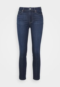 Jeans ajustados de color azul oscuro diseñados con una silueta ceñida, que cuentan con cinco bolsillos, una bragueta con botón y costuras en contraste para mayor detalle.