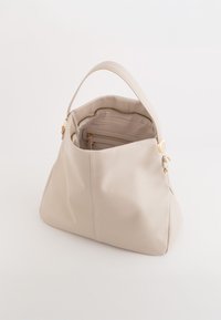 Beżowa skórzana torebka o miękkiej strukturze, z jednym uchwytem na górze i zamykaną na zamek kieszenią wewnętrzną. Akcenty w kolorze złota.