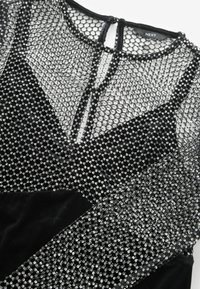 Corset de catifea neagră cu un overlay din plasă transparentă, brodat cu mărgele. Plasa are un model hexagonal și accente argintii strălucitoare. Închidere la spate tip cheie.