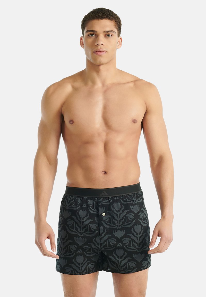 Černé šortky s květinovým vzorem z lehké tkaniny. Elastický pas s knoflíkovým zapínáním vpředu.