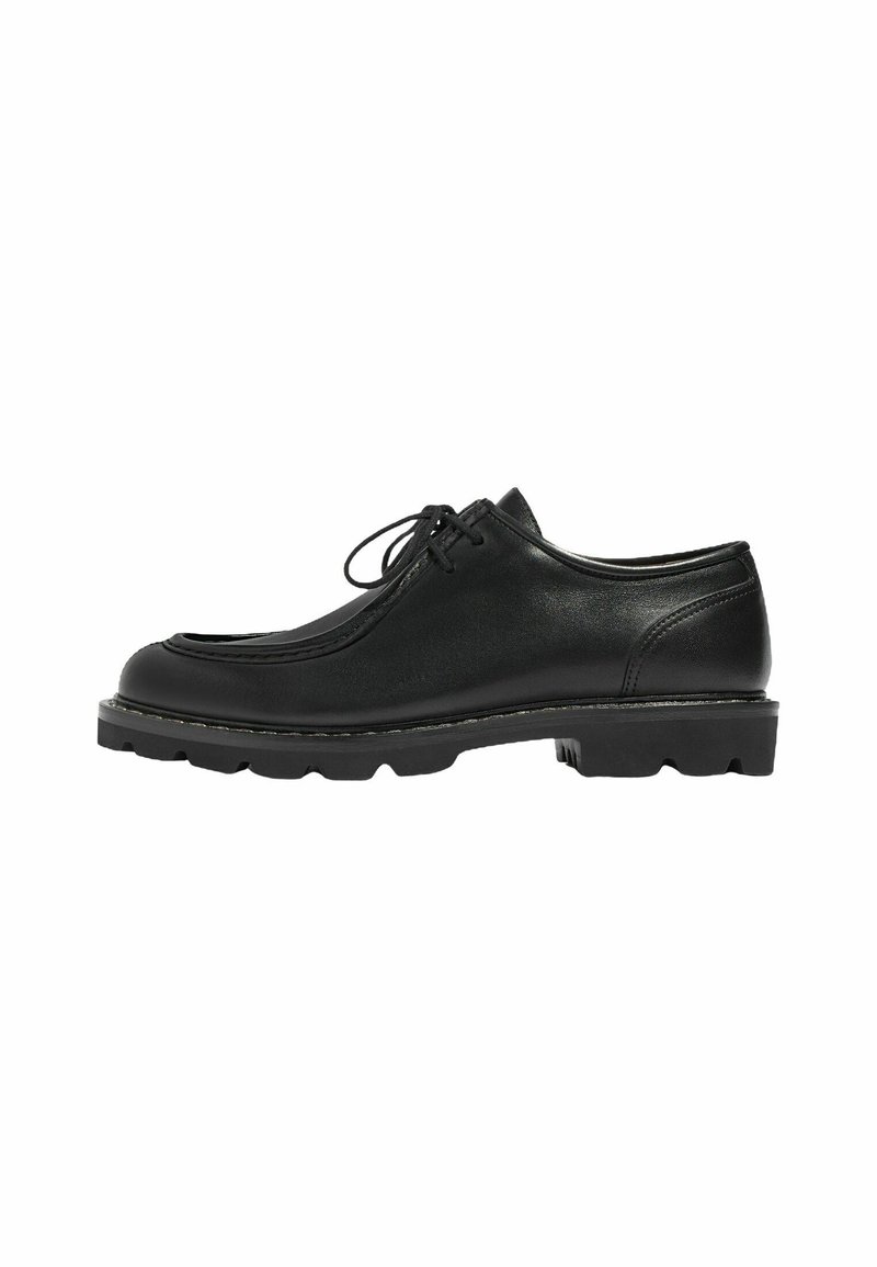 Scarpa in pelle nera con punta arrotondata, cuciture visibili e design con lacci. Suola piatta e strutturata che migliora la presa e la stabilità.