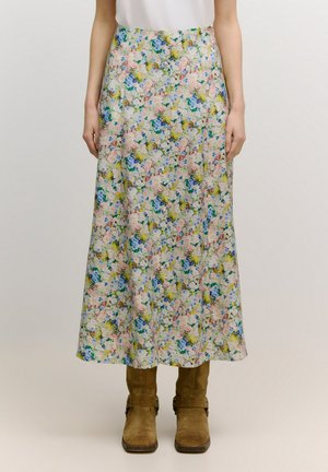 Floral lange rok met een pastel palet, featuring blauwe, roze en gele bloemen, gemaakt van lichte stof, gecombineerd met bruine laarzen.